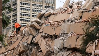 Pessoas observam um prédio desabado no bairro de Altamira após um terremoto em Caracas, em 24 de junho de 2026 | Crédito: Federico Parra / AFP